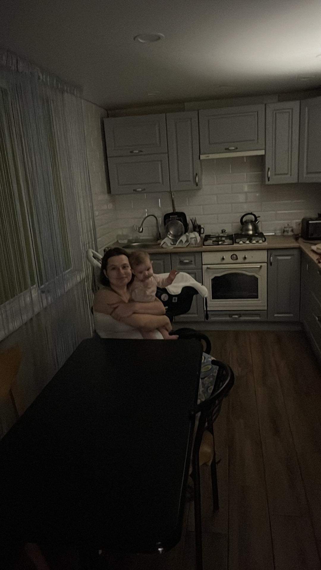 Mum and baby sitting in kitchen at a table under dim light