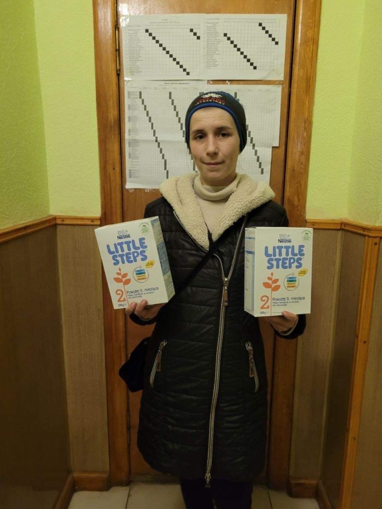 Lady holding packs of powdered milk given as aid