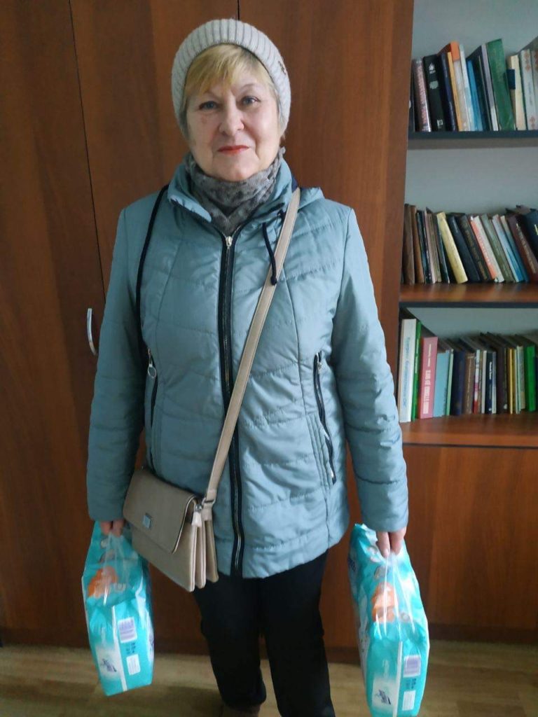 Lady holding packs of nappies given as aid