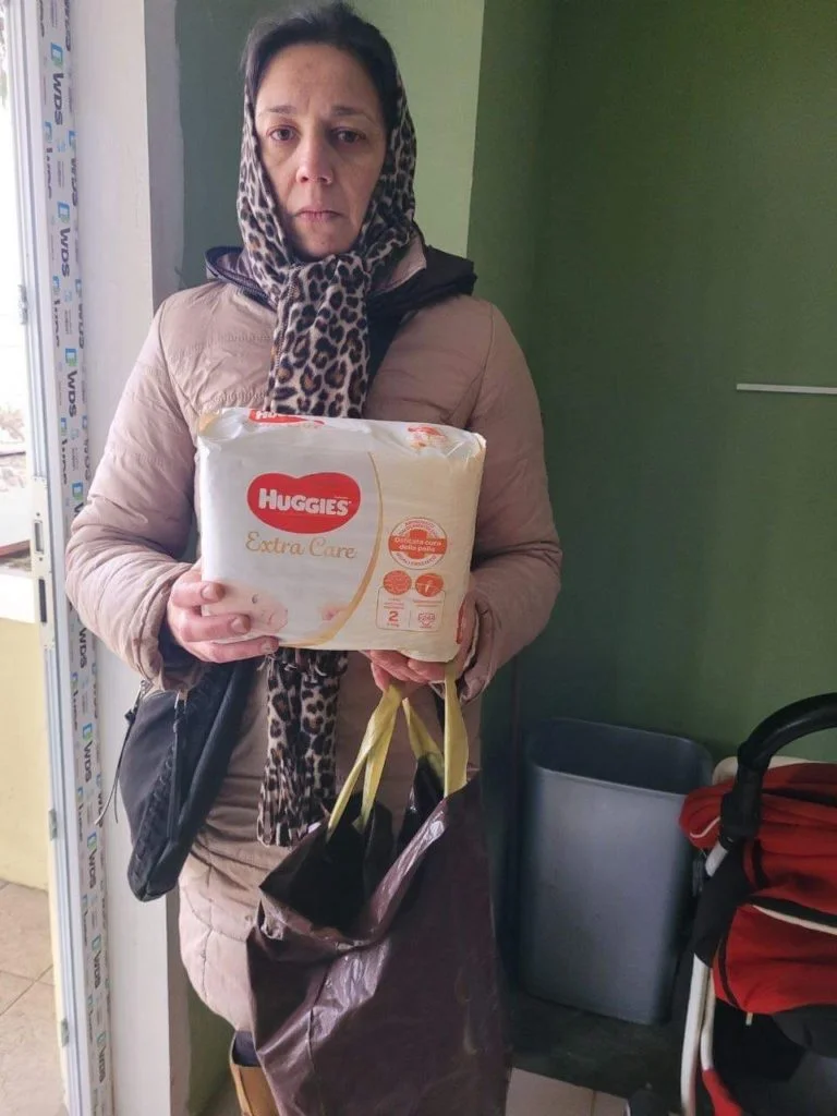 Lady holding a pack of nappies given as aid