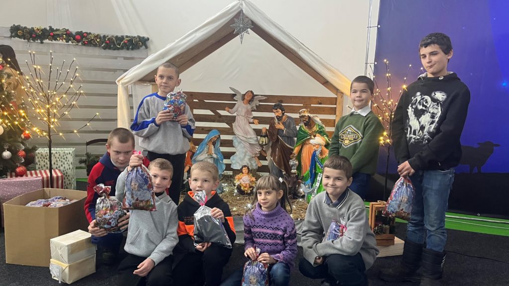 Children who have received presents from the Centre this Christmas standing and sitting in front of a nativity scene