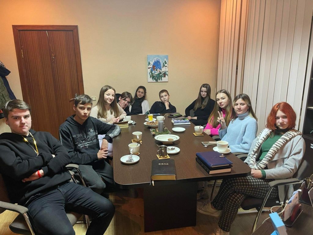 Youth gathered around a table during a Bible study session they have requested.