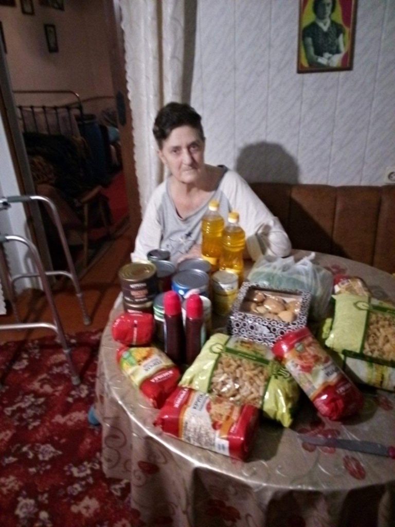 Lady sitting at a table displaying the food aid provided to her.