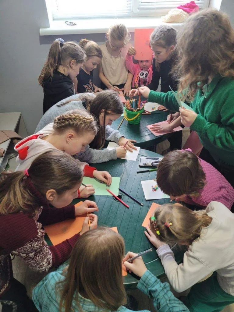 Children at the Centre colouring and drawing pictures around tables.