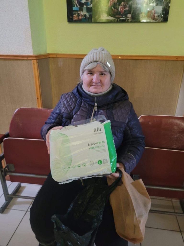 Elderly lady seated with the aid parcel she has received.