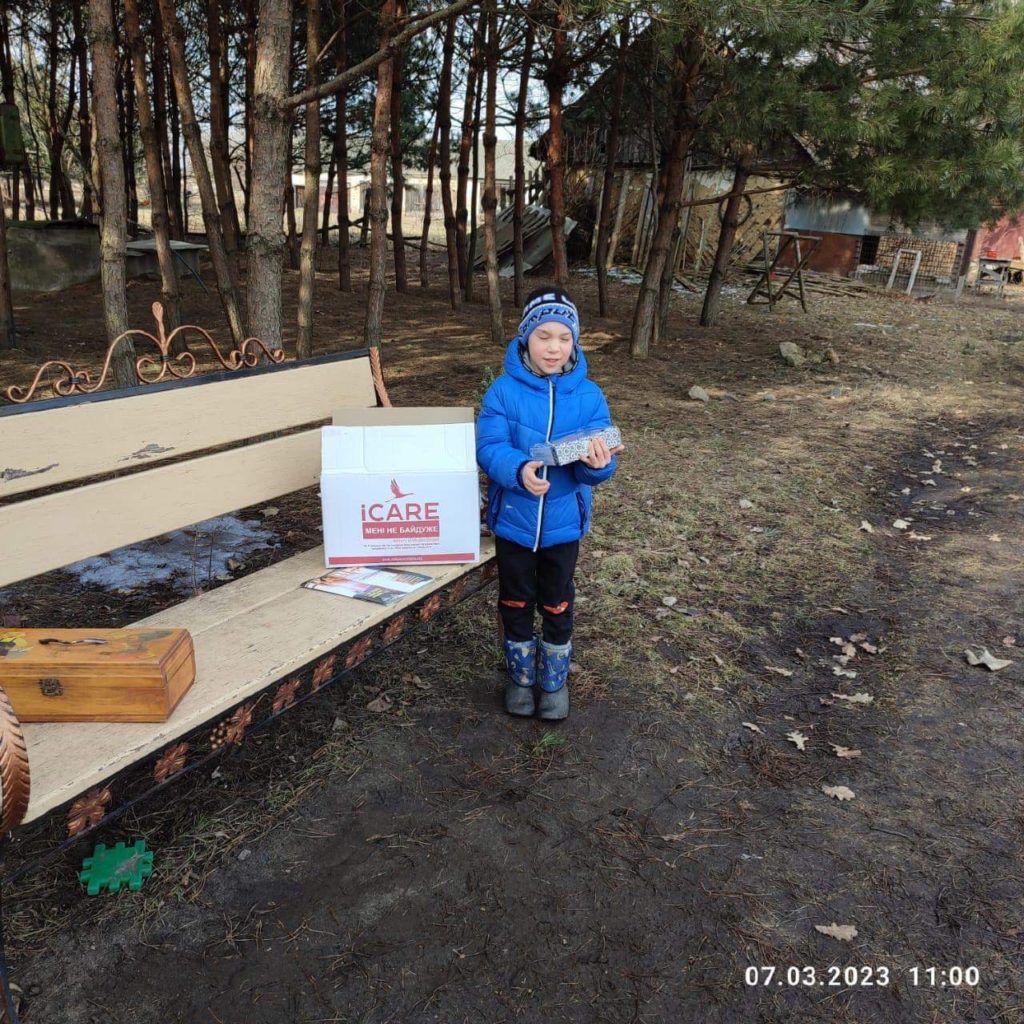 Young child standing next to an iCare aid package which is on a bench