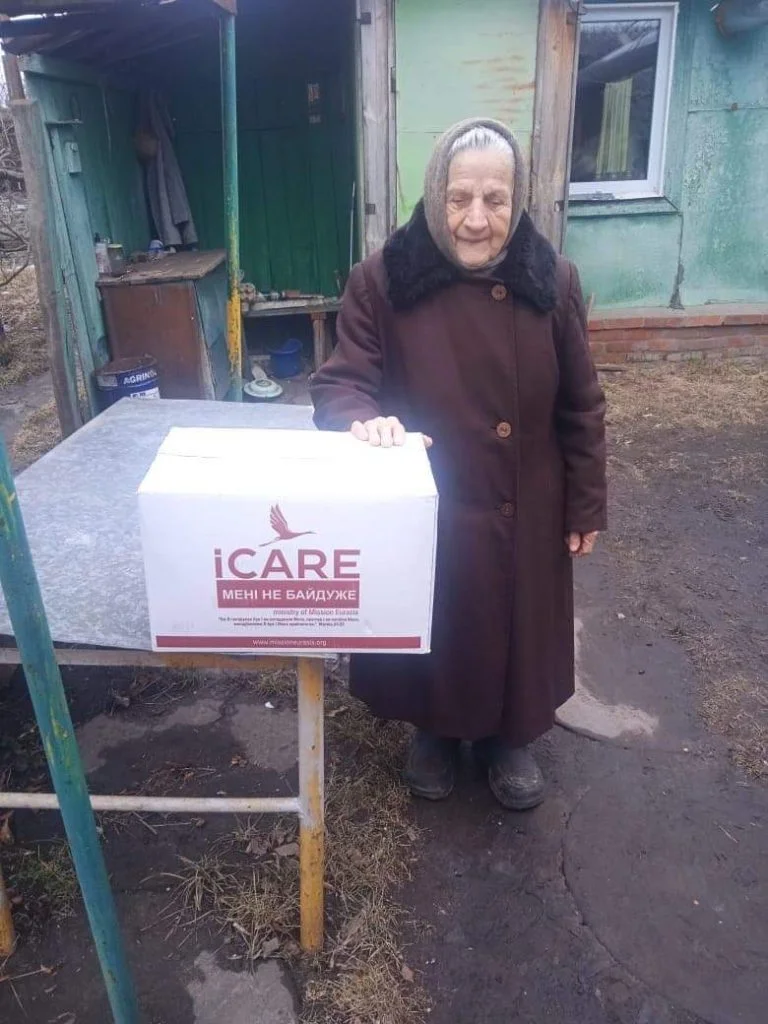 Lady standing next to an iCare aid package
