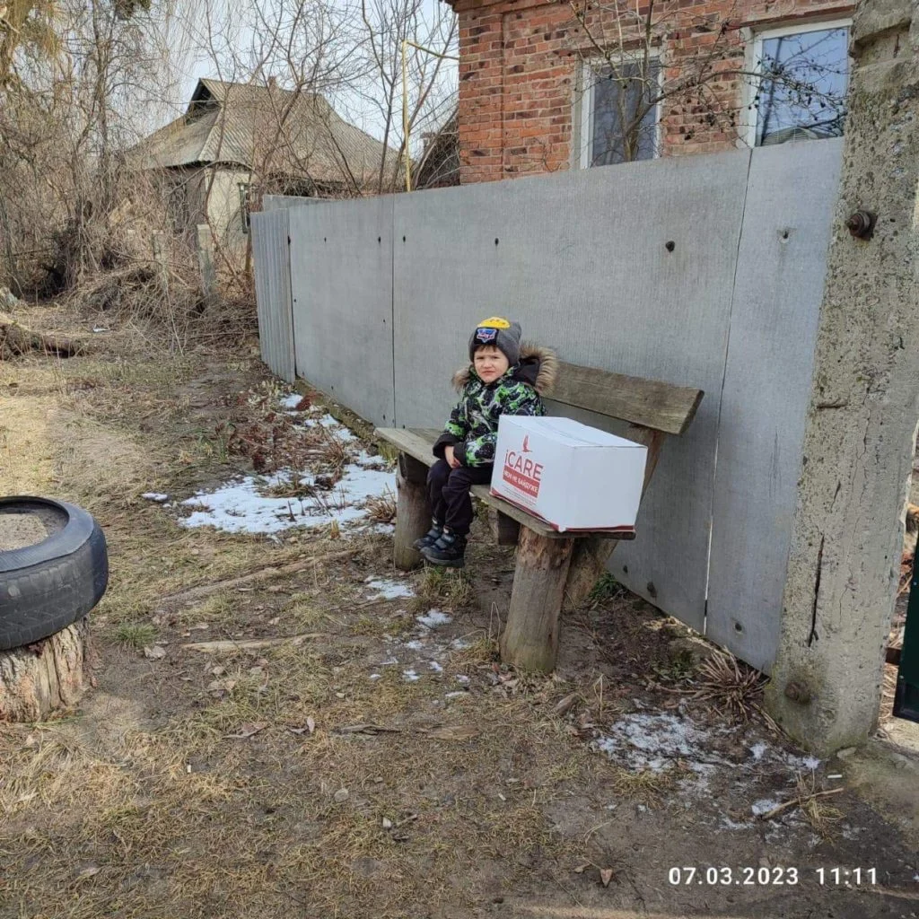Young boy sitting next to an iCare aid package