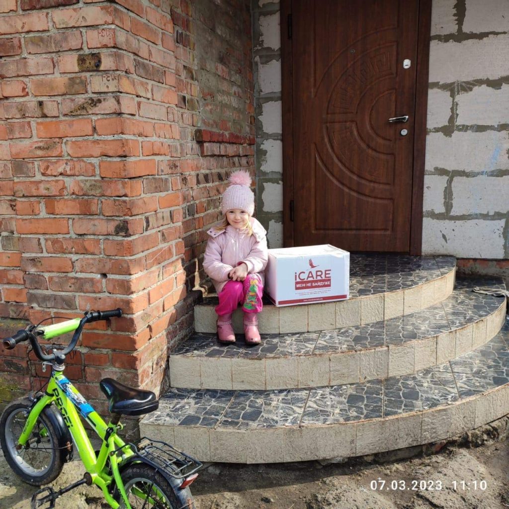 Young girl sitting next to iCare aid package