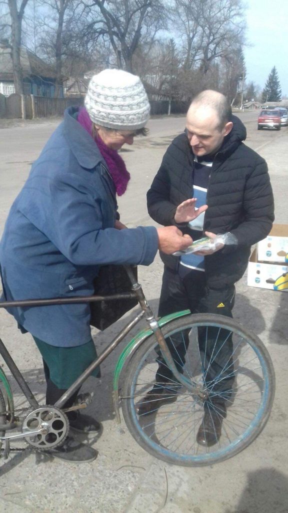 Lady with bicycle in Budylka receiving packs of seeds