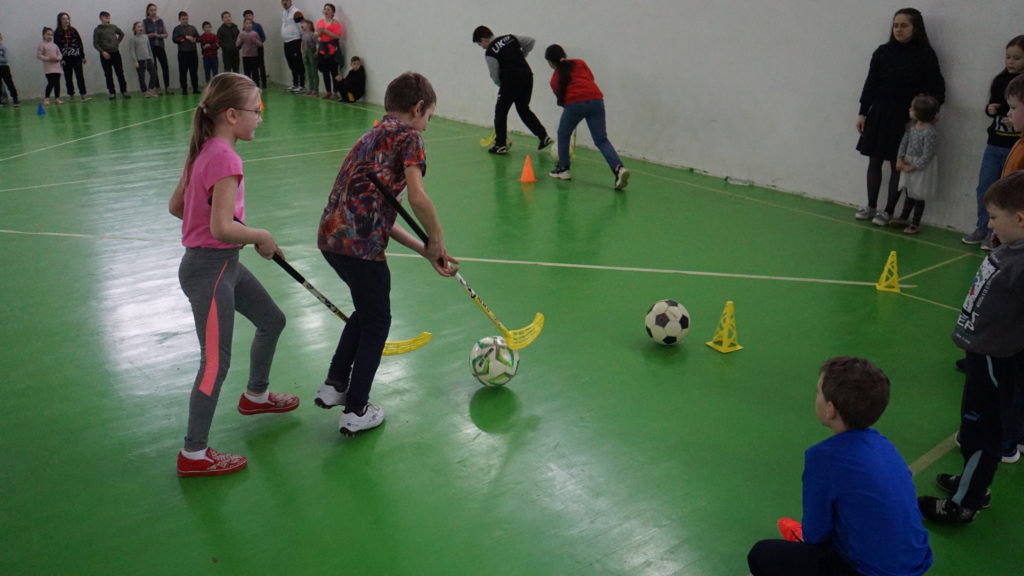 Children playing hockey in the sports hall