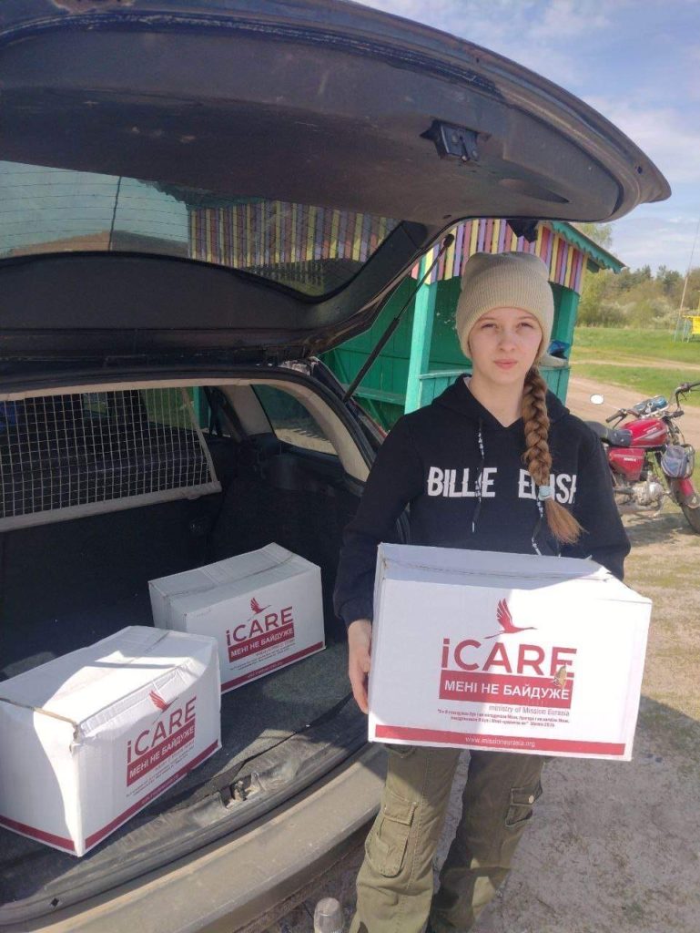 Girl at the rear of a car holding an iCare package