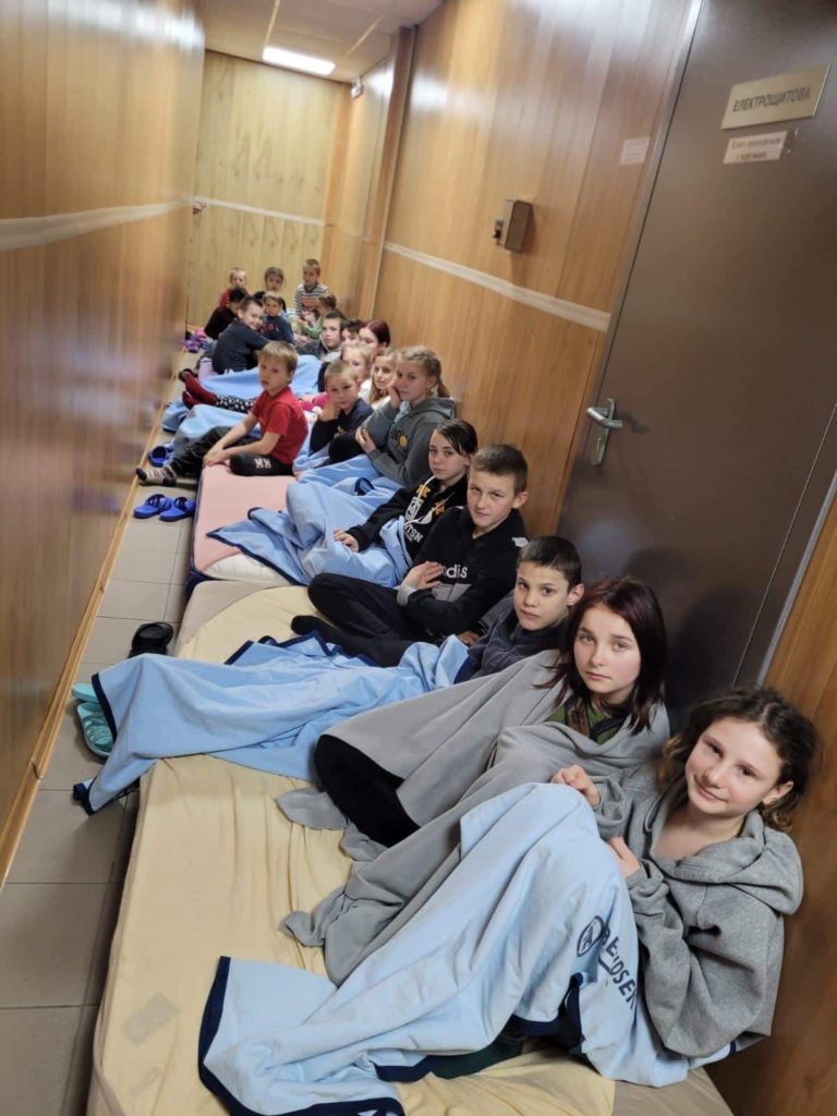 Orphanage children sitting on mattreses in a hallway