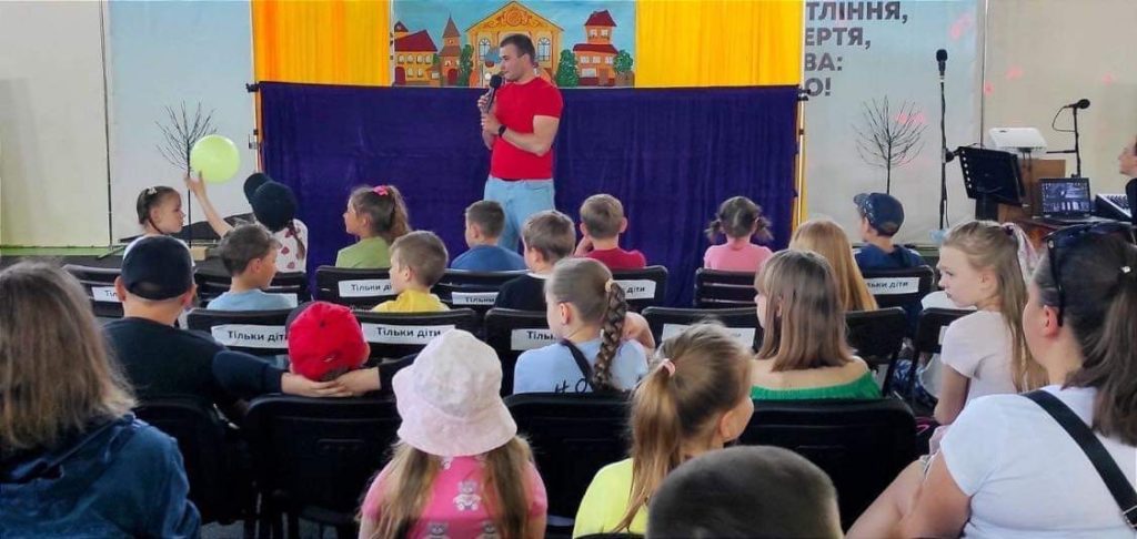 Children sitting listening a a team member speak.