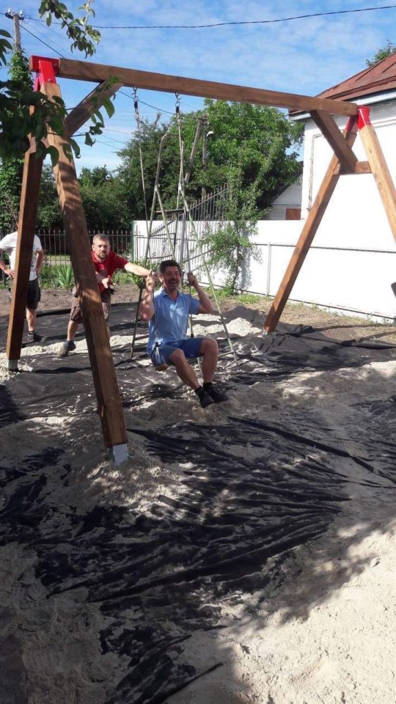 Man playing on a newly installed children's playground swing