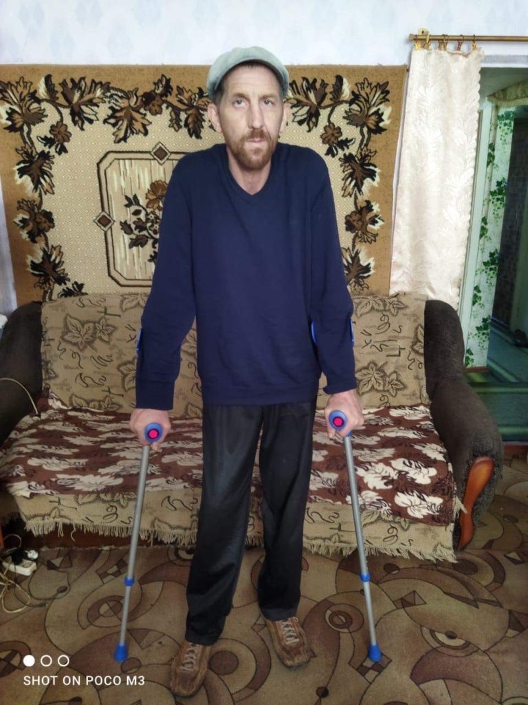 Man using donated crutches to stand up on his own