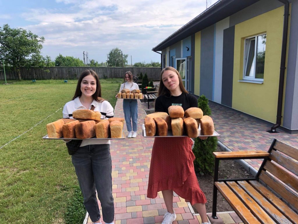 Two girls carrying a tray of freshly baked loaves of bread