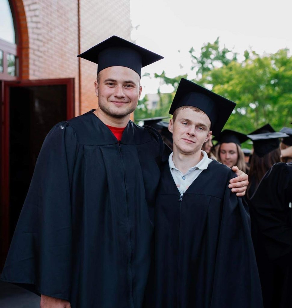 Valentine and “Farmer” Sergey posing for a picture in their graduation gowns at their graduation cermony