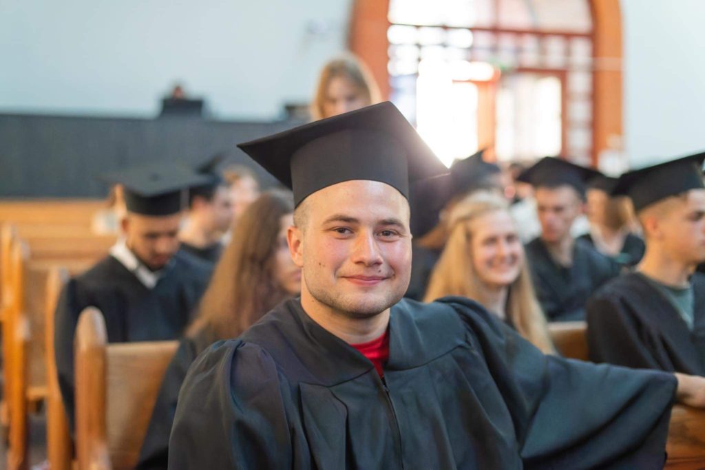 Valentine sitting in a pew in his graduation gown at his graduation ceremony