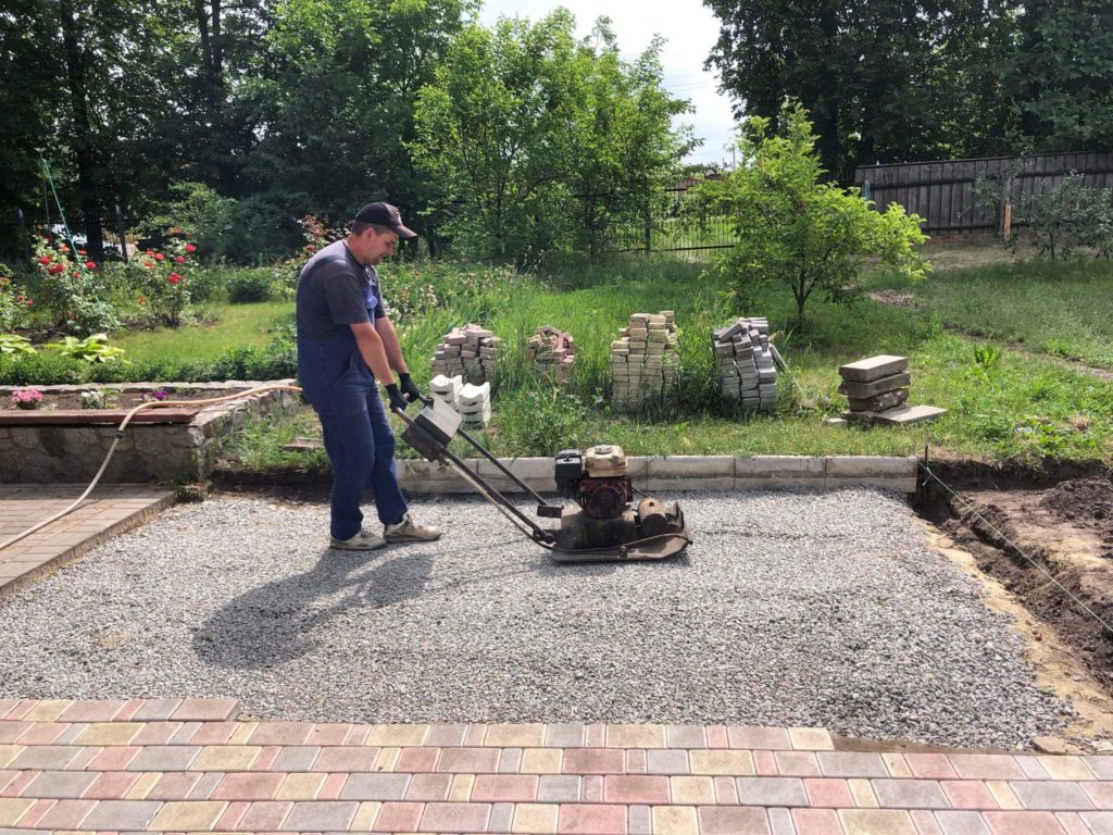 Man using a compactor machine to compact the ground ready for paving to go down in the playground