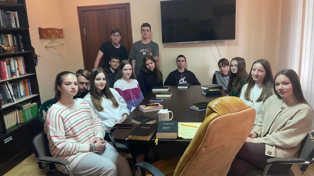 The youth group sitting around a table during a meeting