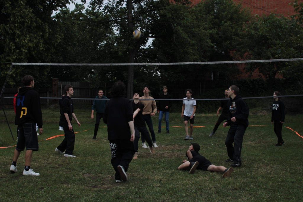 The youth playing volleyball over a net outside