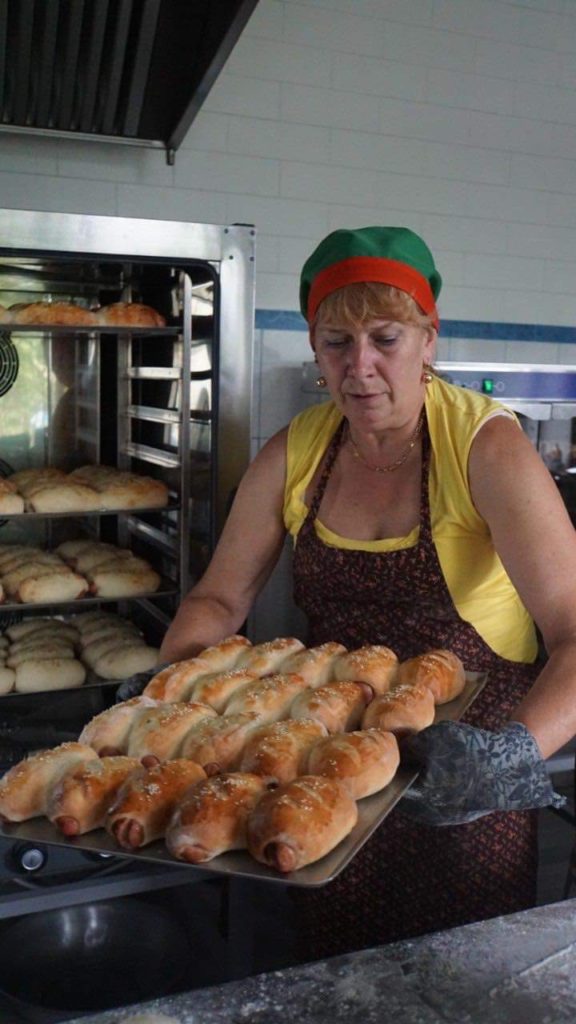 A lady taking freshly baked bread out of the oven