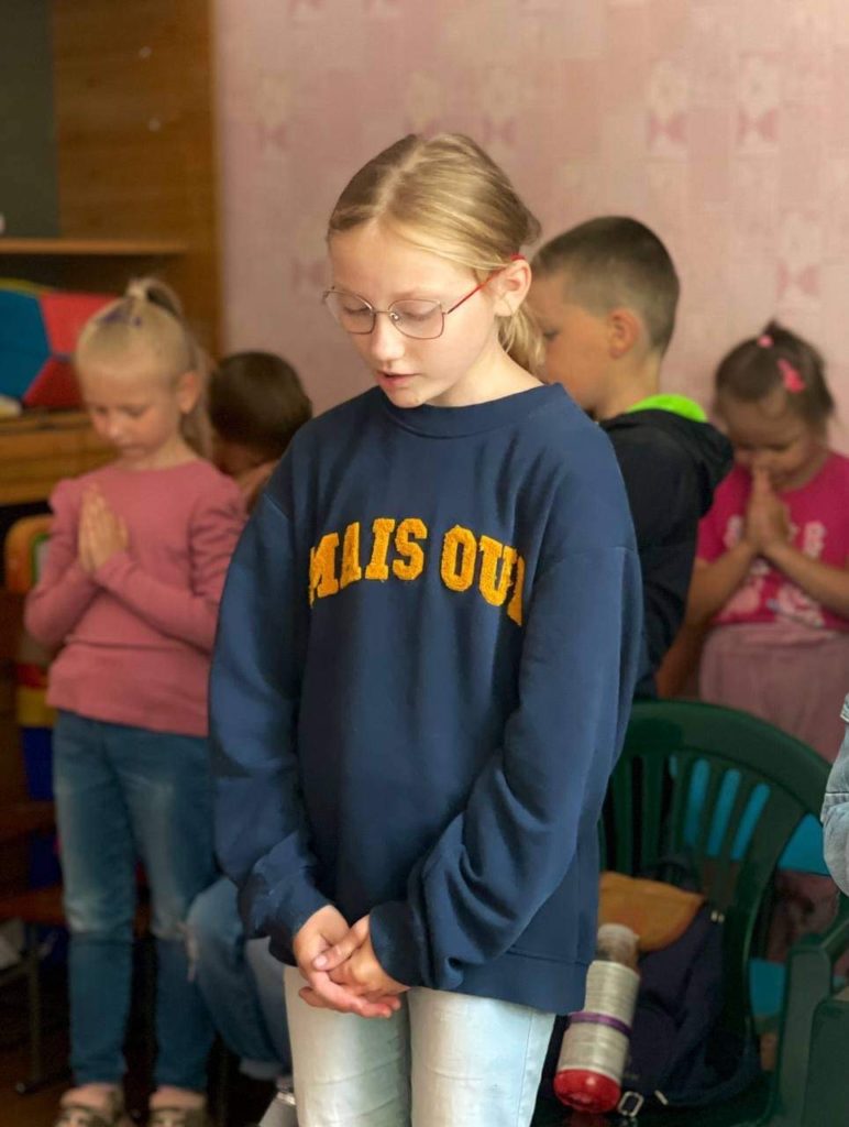 A young girl standing praying.