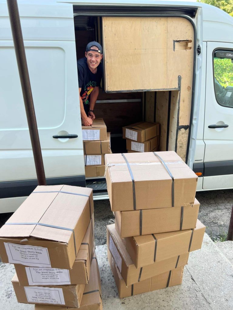 Boxes of the Jesus Storybook bible stacked next to the van from which they are being unloaded