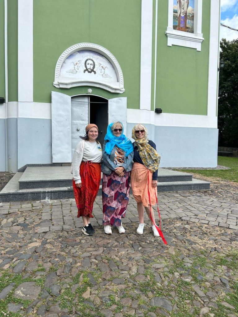 Karen, Sandra and Alla standing in front of an orthodox church dressed in appropriate clothes to go inside