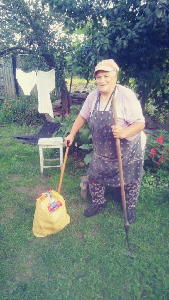 A woman standing in her garden supported by walking stick with a bag of aid provided by the Centre on the ground in front of her