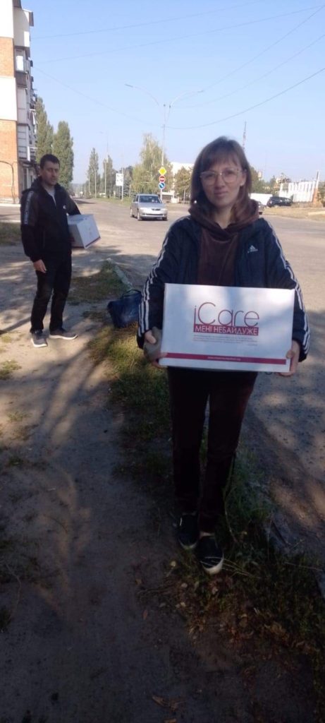 Lady holding iCare package standing next to a road
