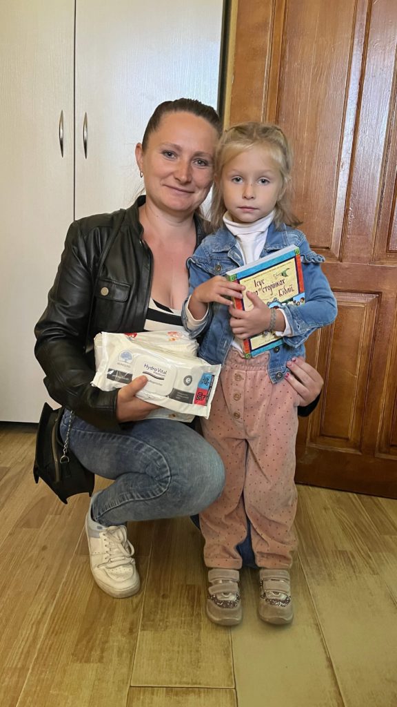 Mum and young daughter holding nappies, baby wipes and a copy of the Jesus Storybook Bible
