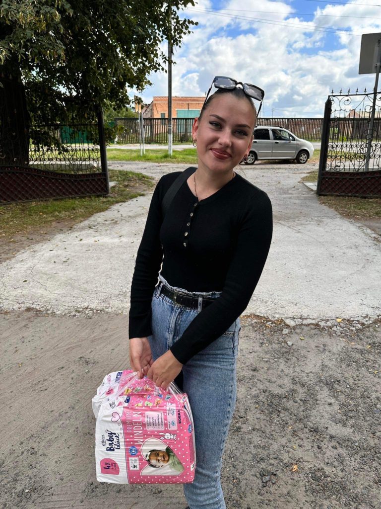 Young mum holding packs of nappies given out at Lyuba's Monday meetings.