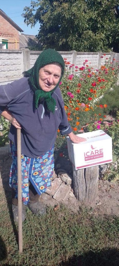 Older lady standing in a garden next to an iCare aid package