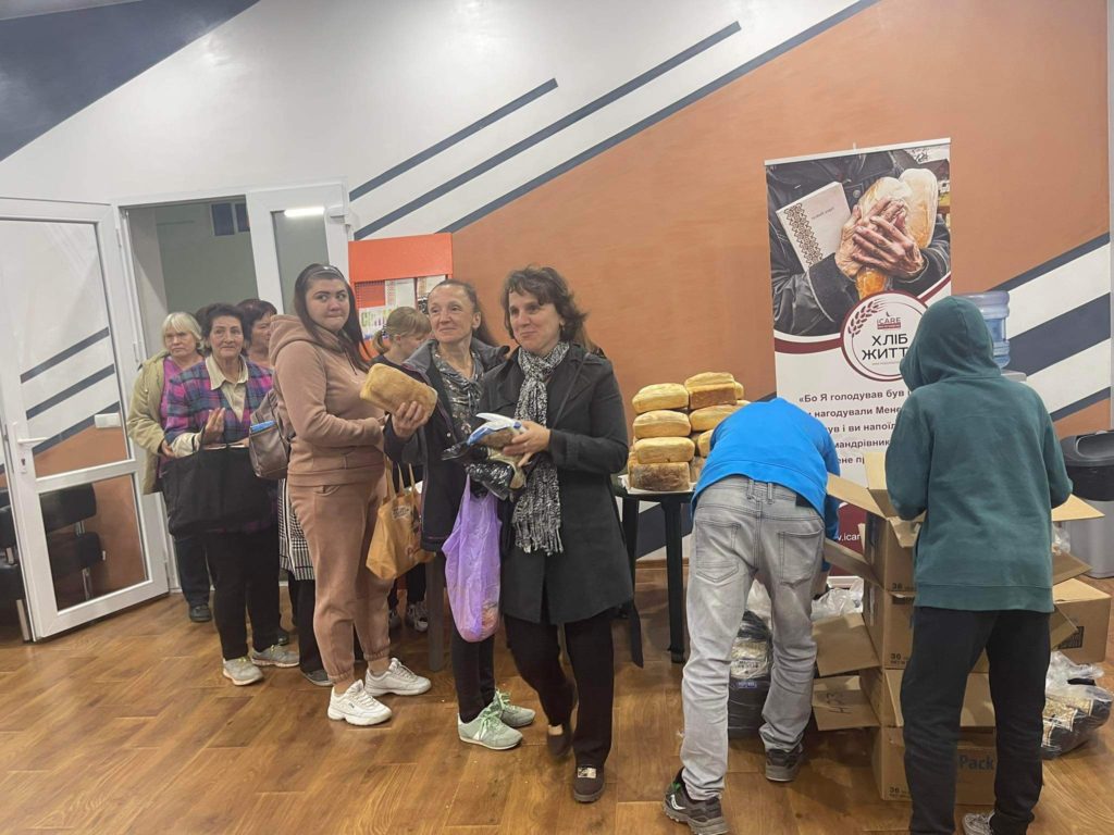 A queue of people in the Centre collecting bread and packets of food