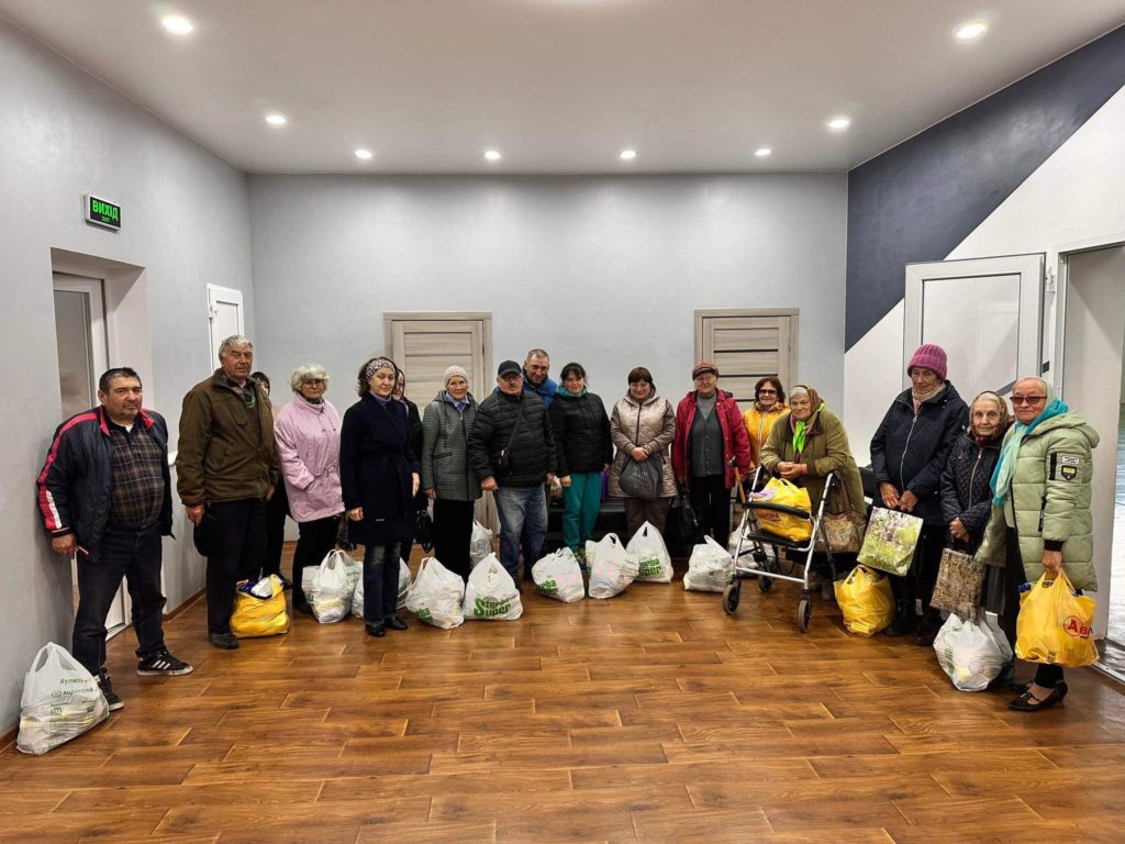 A group of adults from the Inclusive Centre in the hall with bags of food aid provided to them