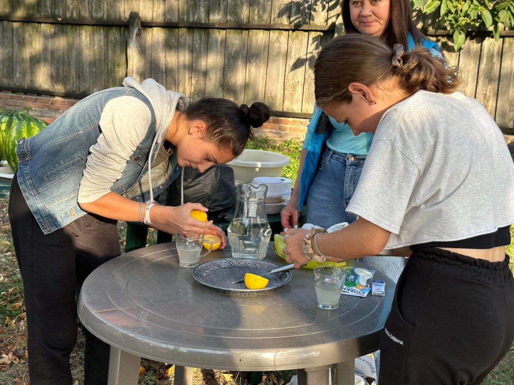 Teenage girls cutting lemons on a garden table outside the Centre