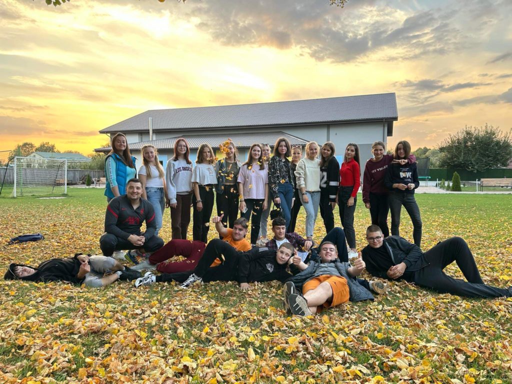 Youth group posing for a photograph in the autumn leaves outside the Centre
