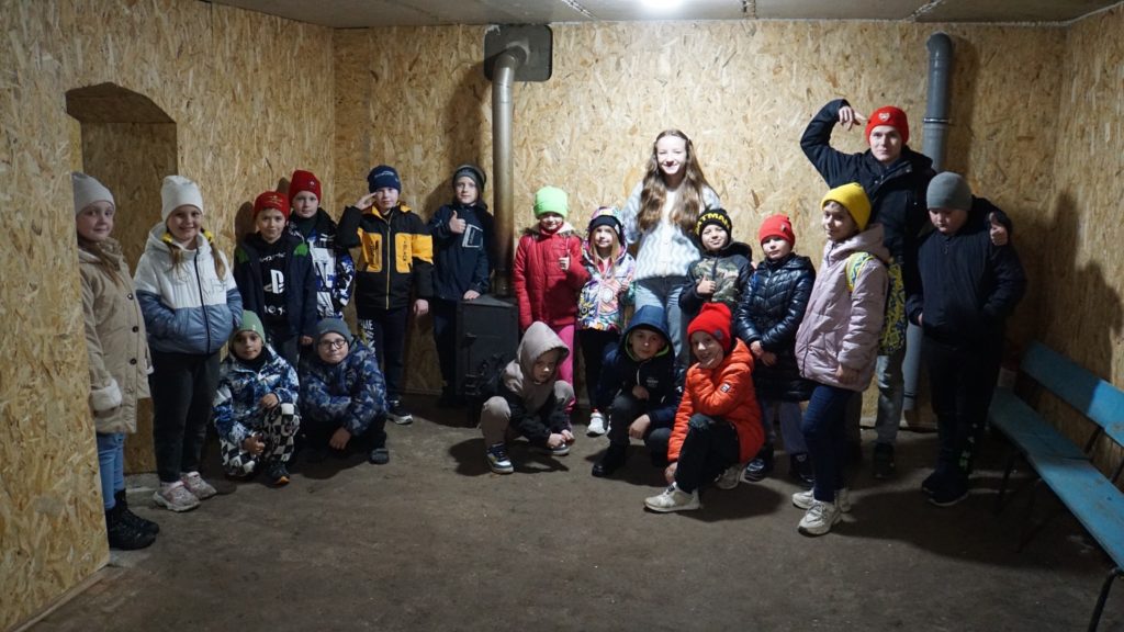Children at the Autumn 2023 camp standing and sitting in the new bomb shelter