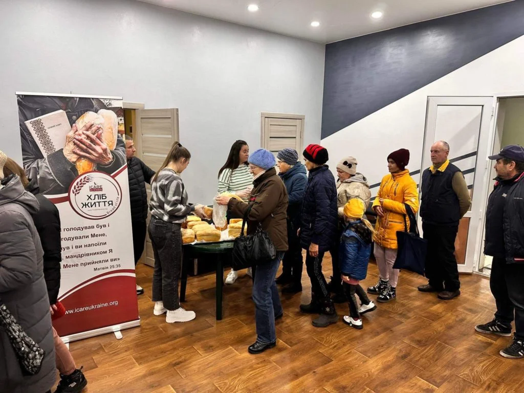 People queuing in the Centre to collect bread from a table