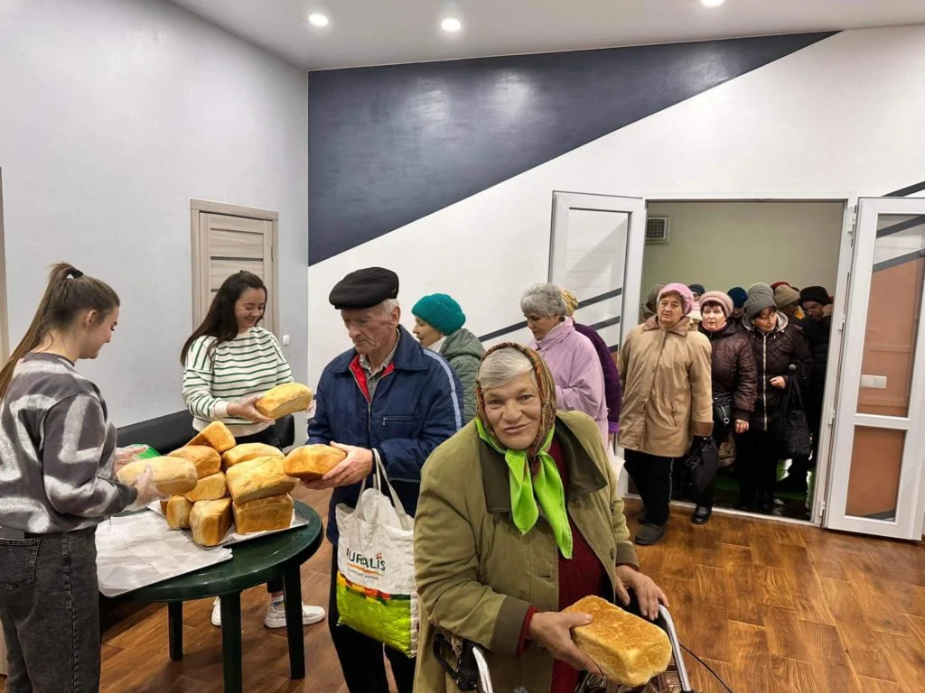 People queuing in the Centre to collect bread from a table