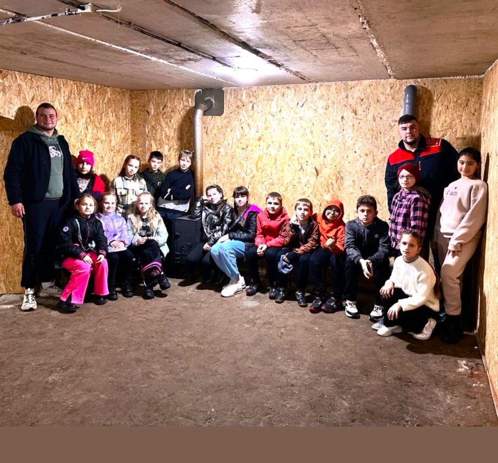 Children at the Autumn 2023 camp staning and sitting in the new bomb shelter