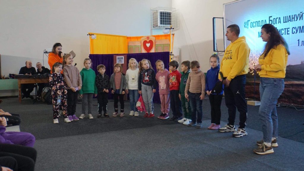 Children at the Autumn 2023 camp standing out the front whilst a leader speaks to them