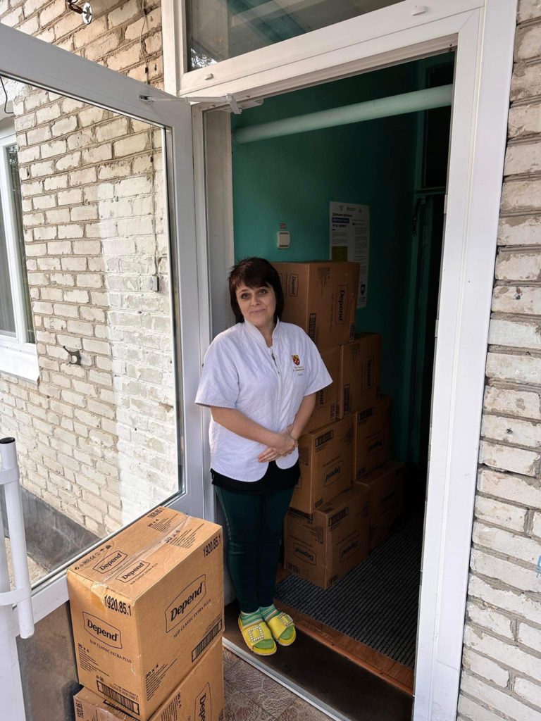 Lady standing in a doorway at the Centre next to boxes of aid