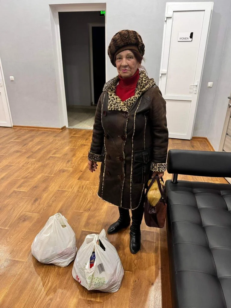 A lady standing in the Centre with two bags of aid gifted to her