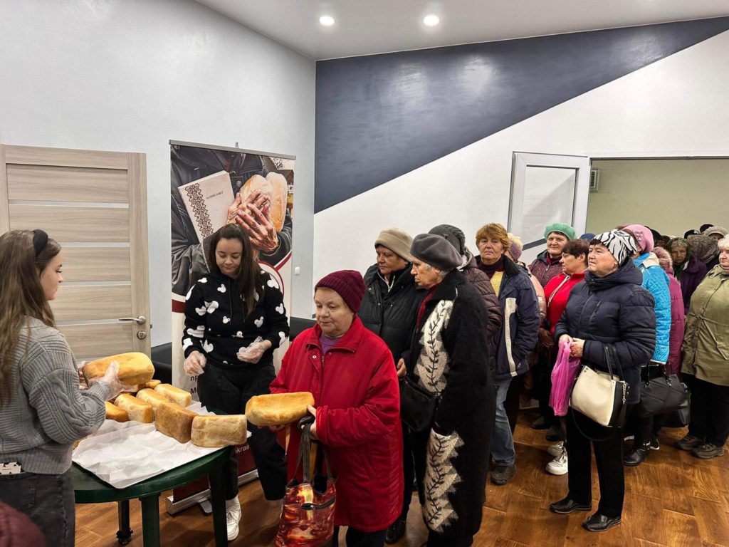 People queuing in the Centre to collect bread from a table
