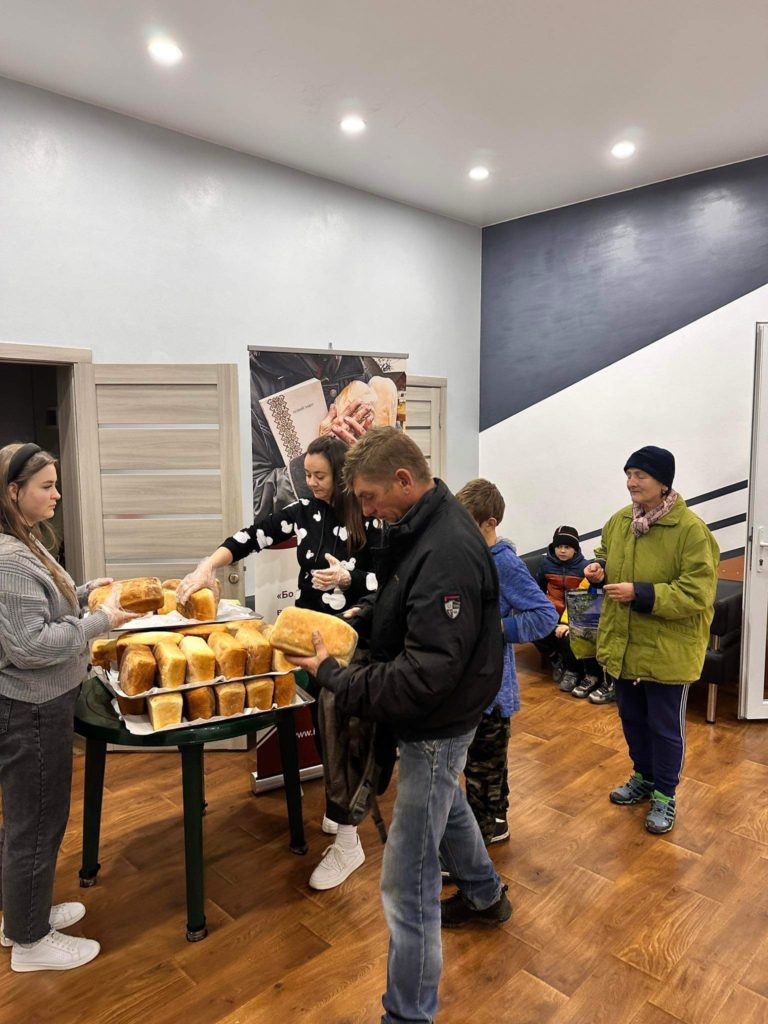 People queuing in the Centre to collect bread from a table