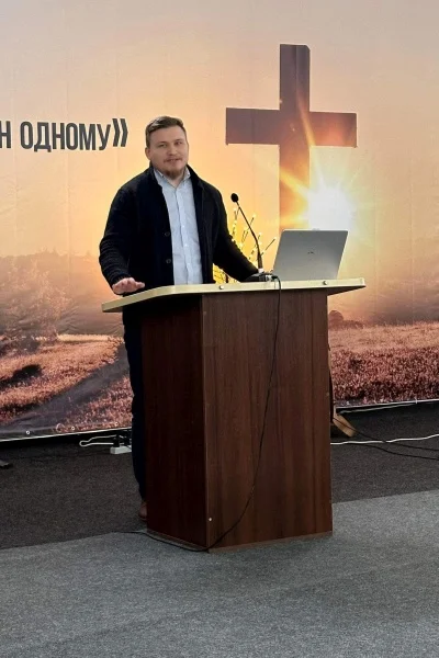 Sasha standing at a lecturn in the church