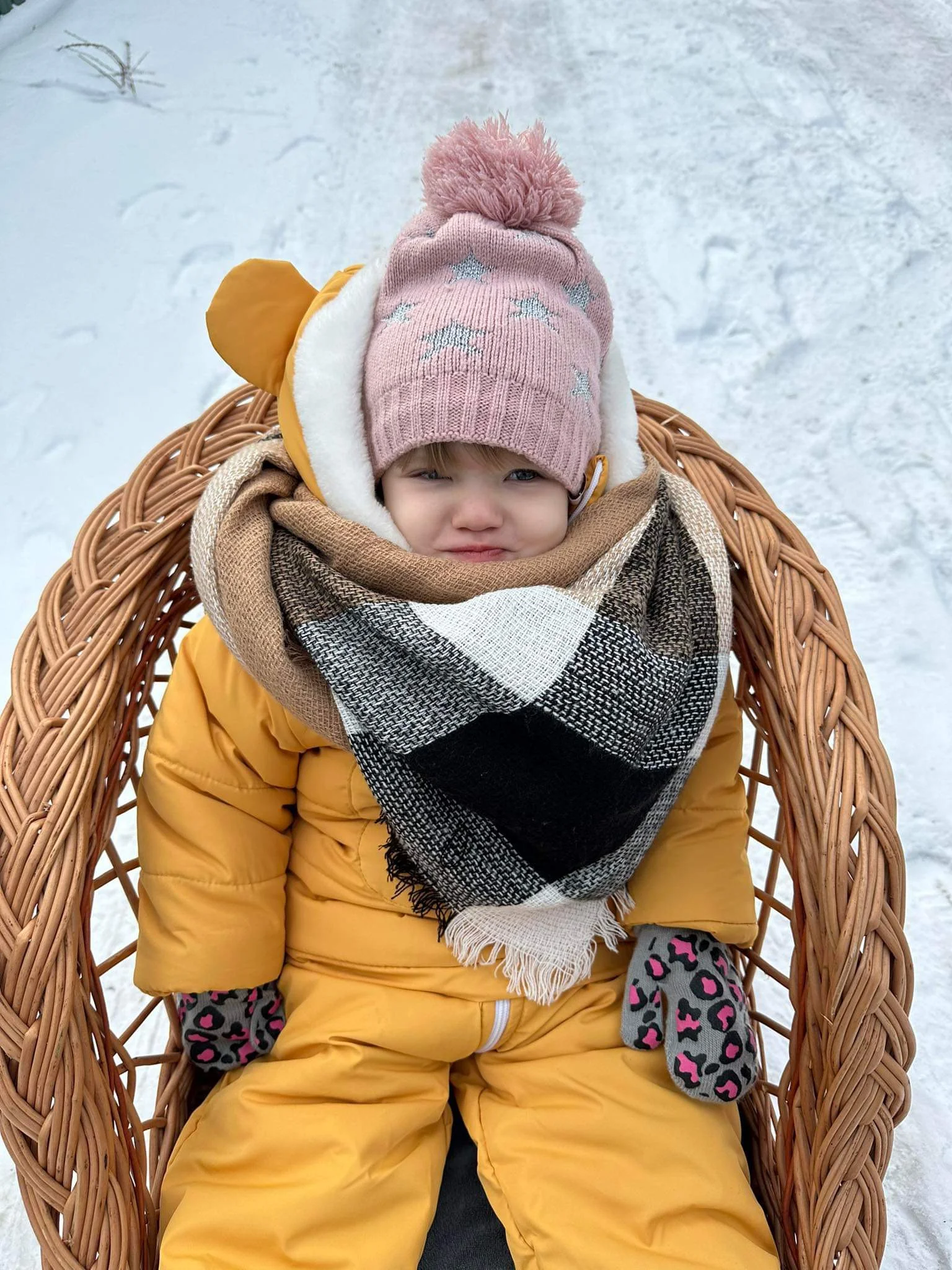 Zoryana wrapped up in thick clothes sat in a wicker chair in the snow